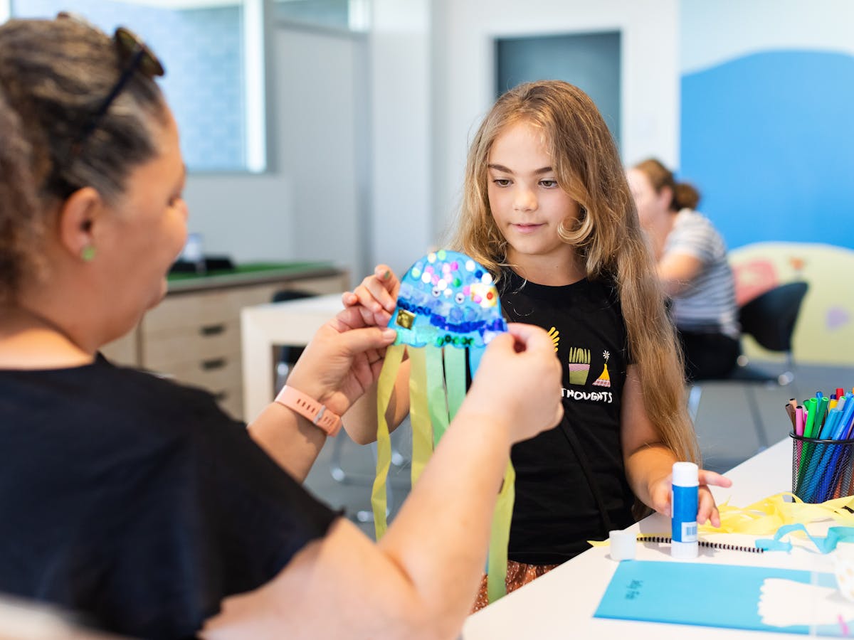 Young girl creating paper jellyfish with guardian