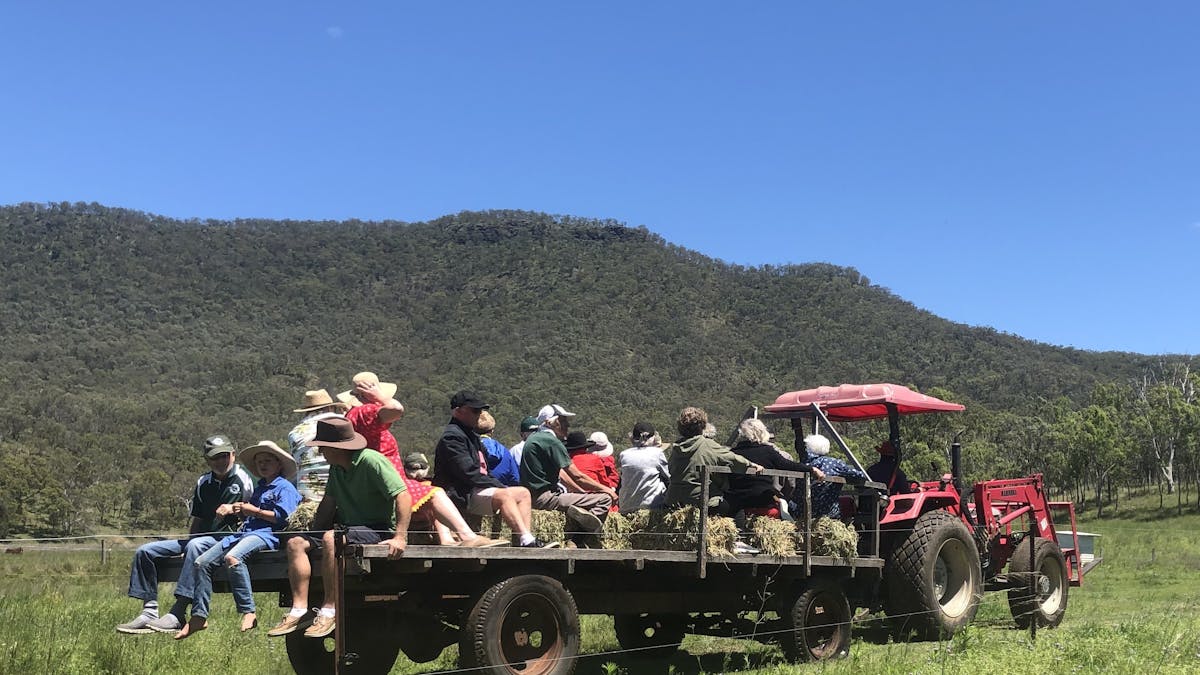 People riding on a haywagon pullled by a tractor