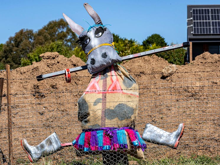 a scarecrow with a donkey head and torso, wearing a bikini top and ballet skirt