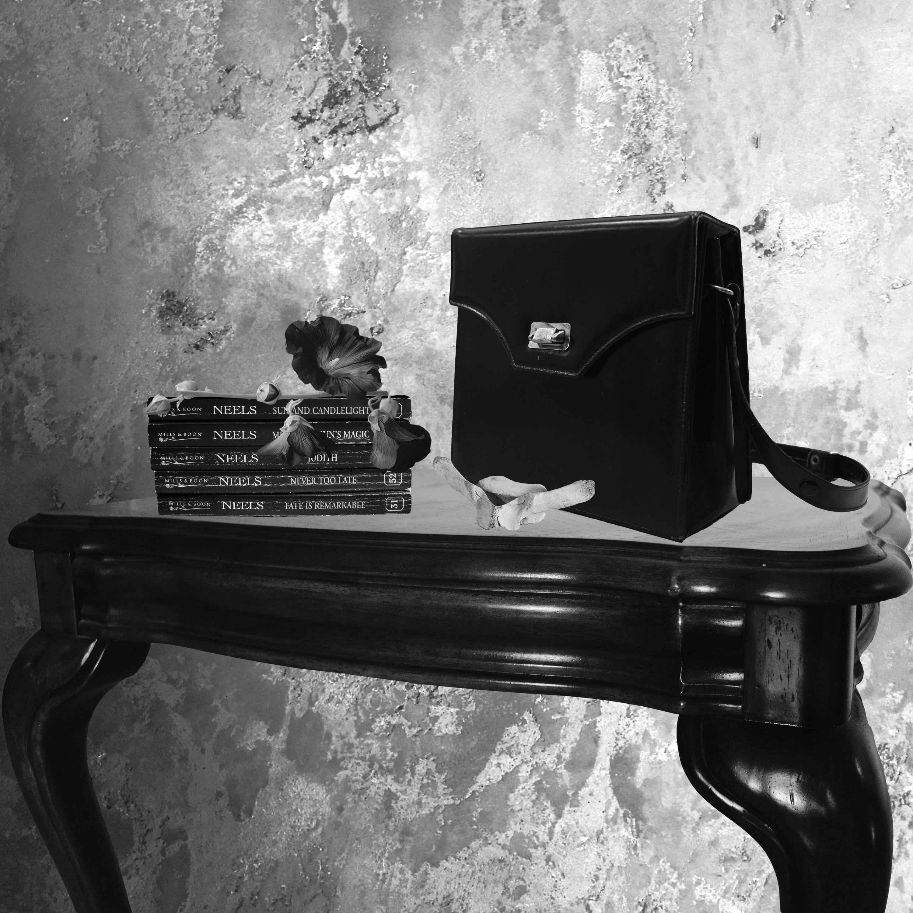 black and white image, satchel, books and flower sitting on table