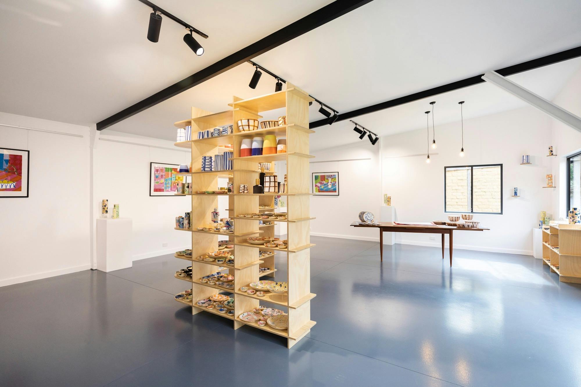 Inside view of the gallery with large shelf in the middle with pots on it.