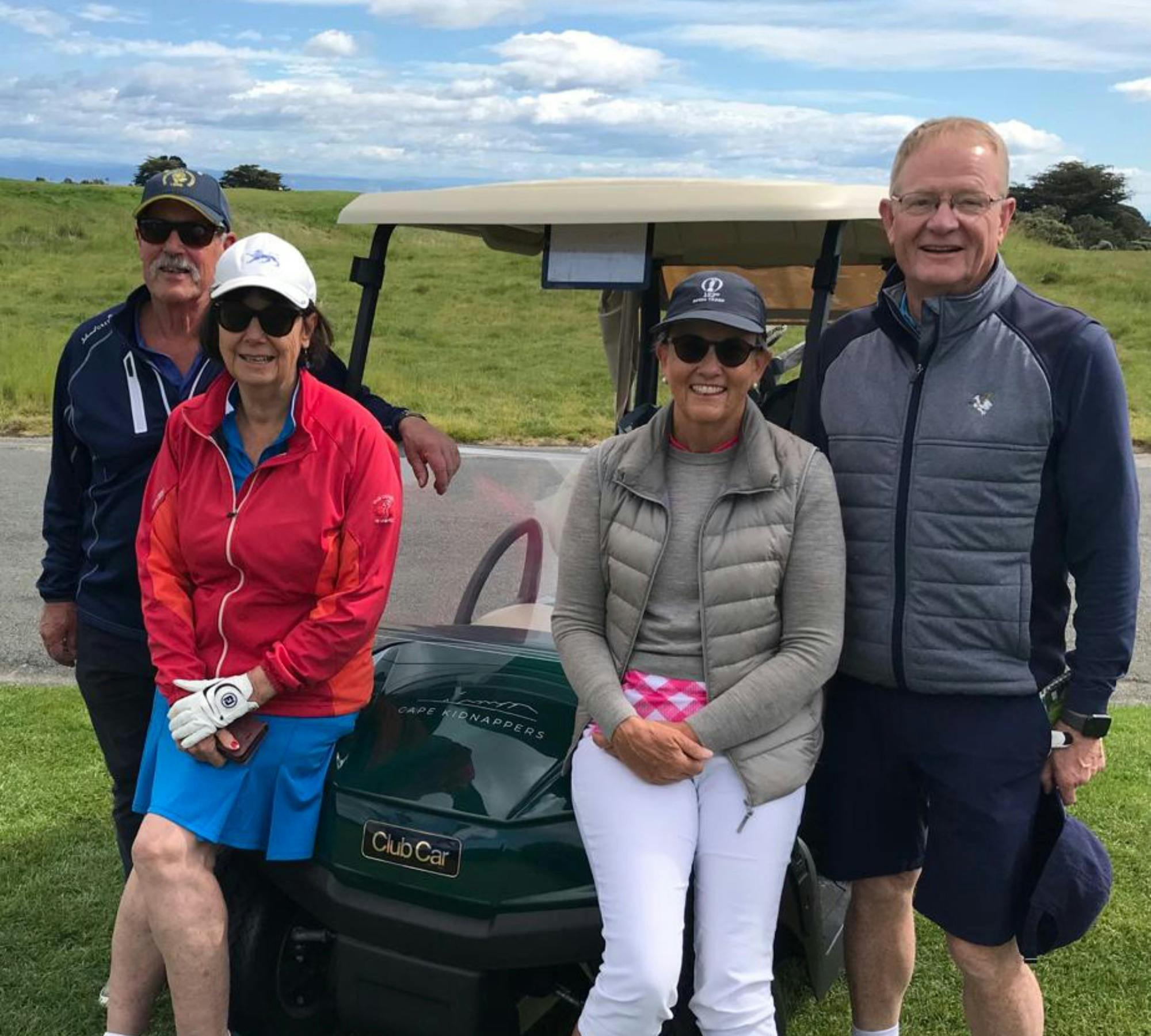 Golfers standing in front of a cart