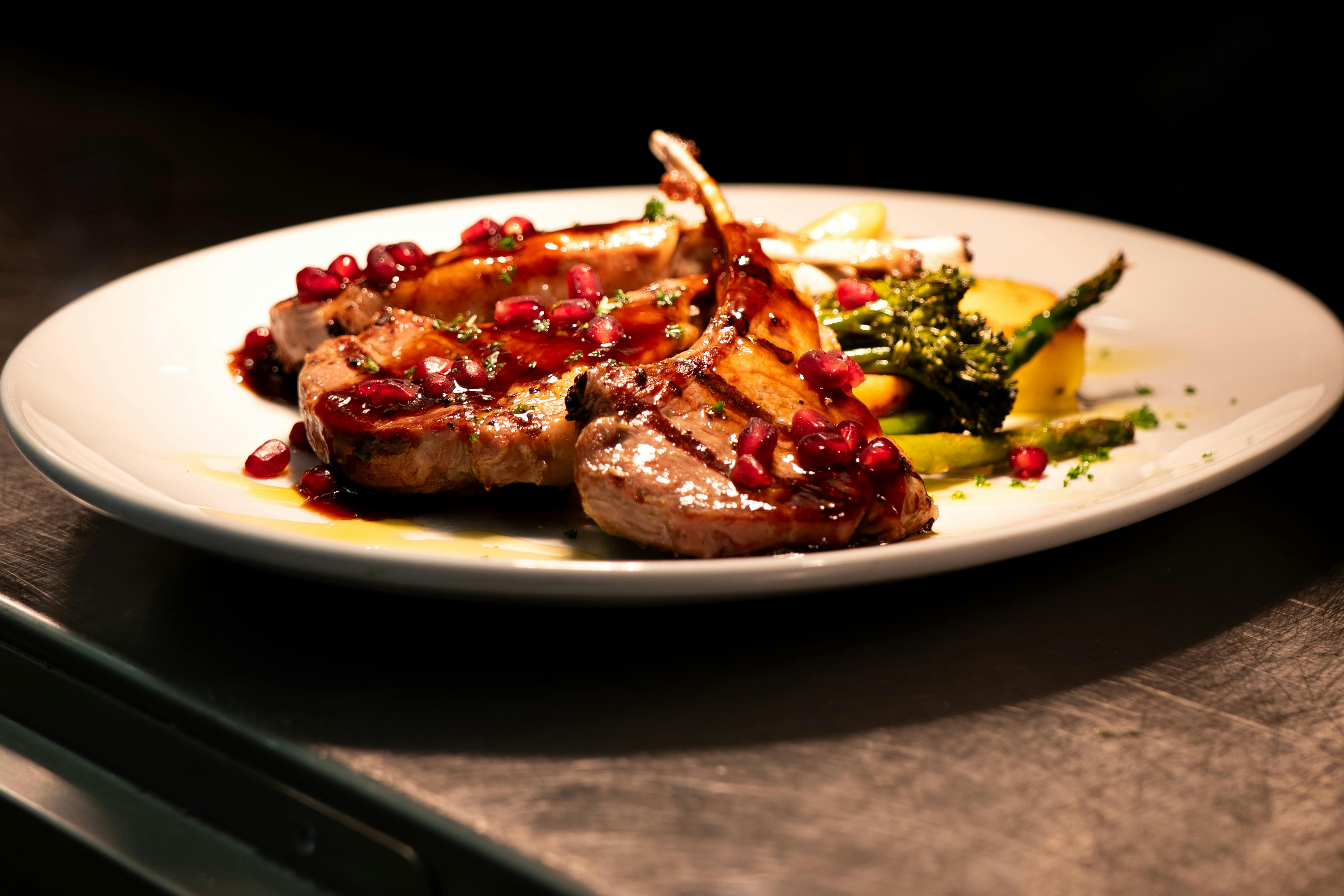 Grilled lamb cutlets with pomegranate glaze and seasonal greens.
