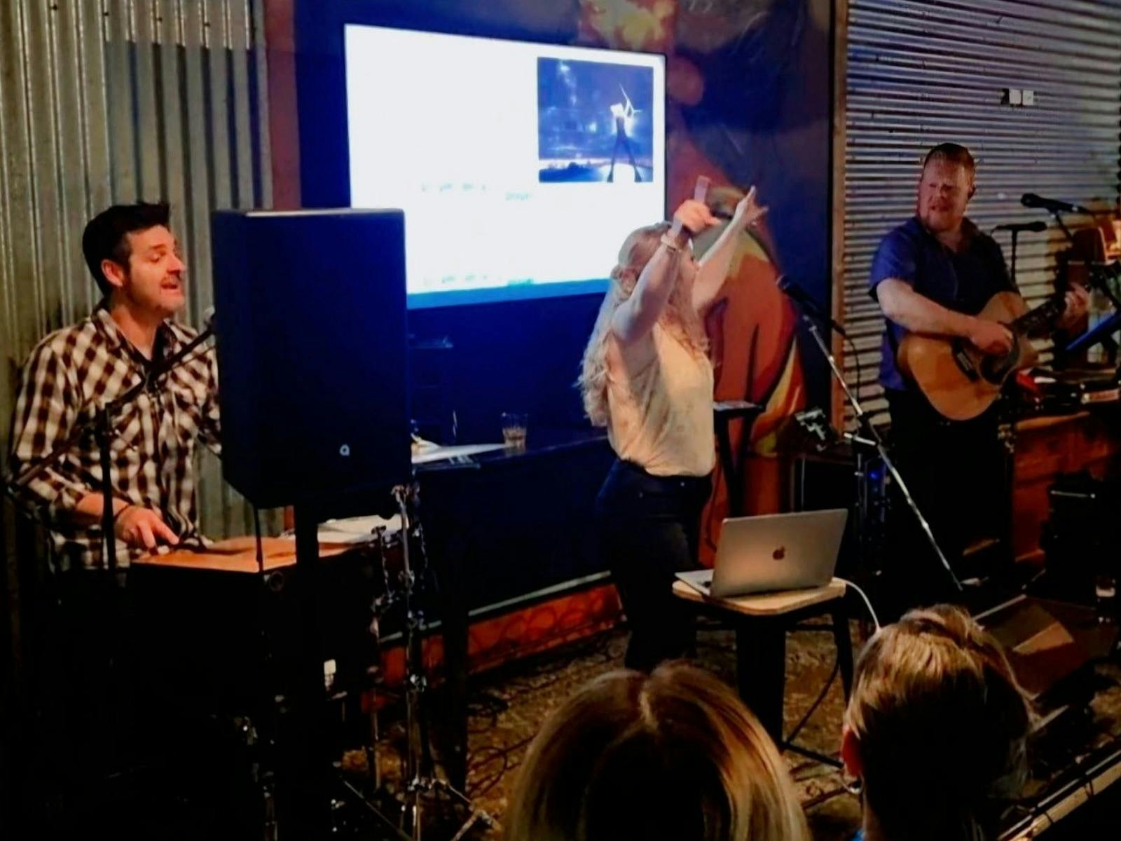 Live indoor music performance with singer, guitarist, and percussionist onstage