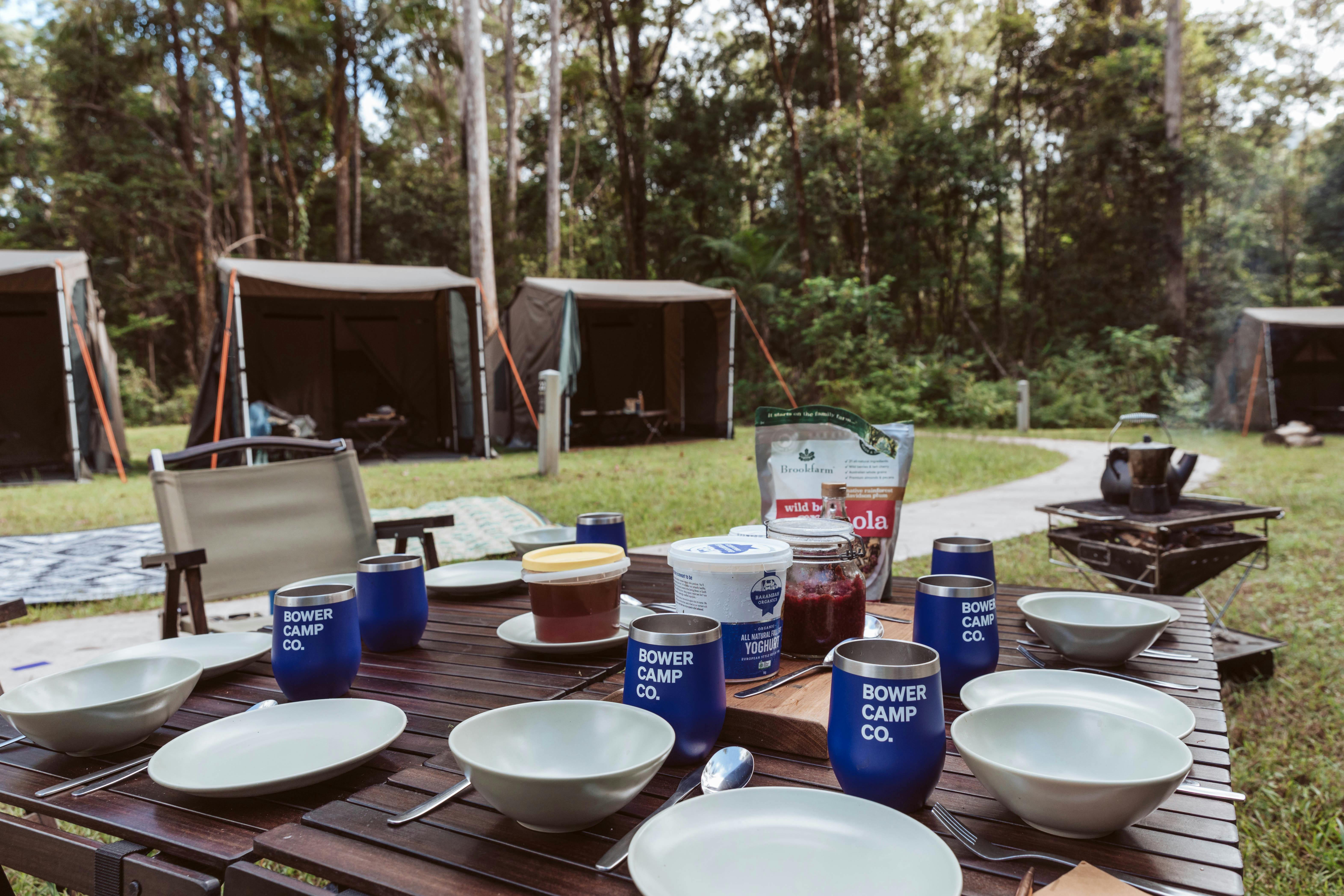 A table laid for breakfast in front of tents set up in the rainforest