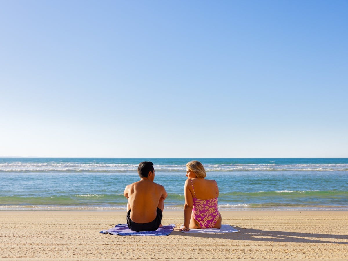 People sitting on the beach looking out at the water People sitting on the beach looking out at the water