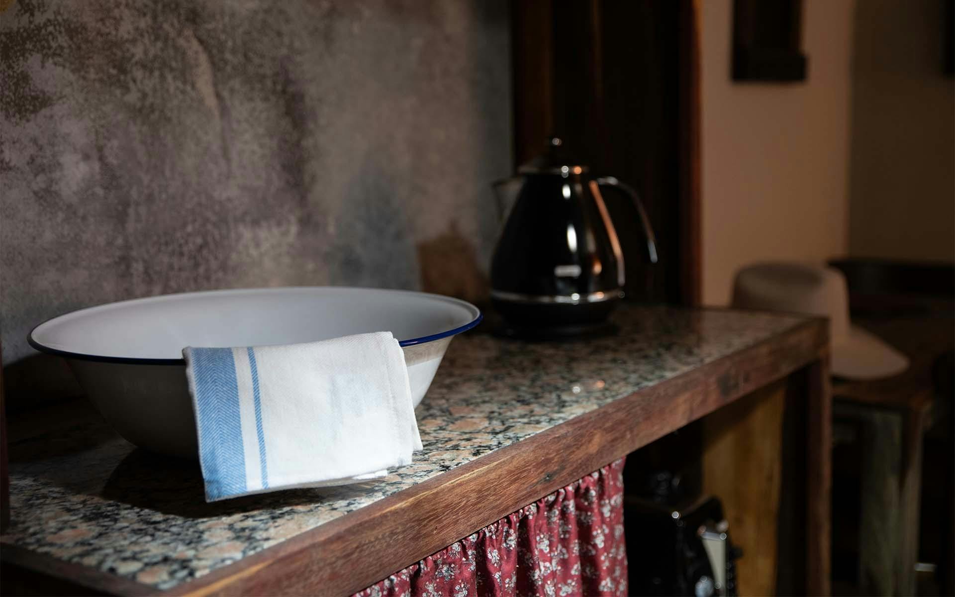 An enamel bowl with a tea towel inside