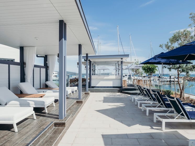 Shot of a pool bar with cabanas on the left hand side and a view of the marina on the right