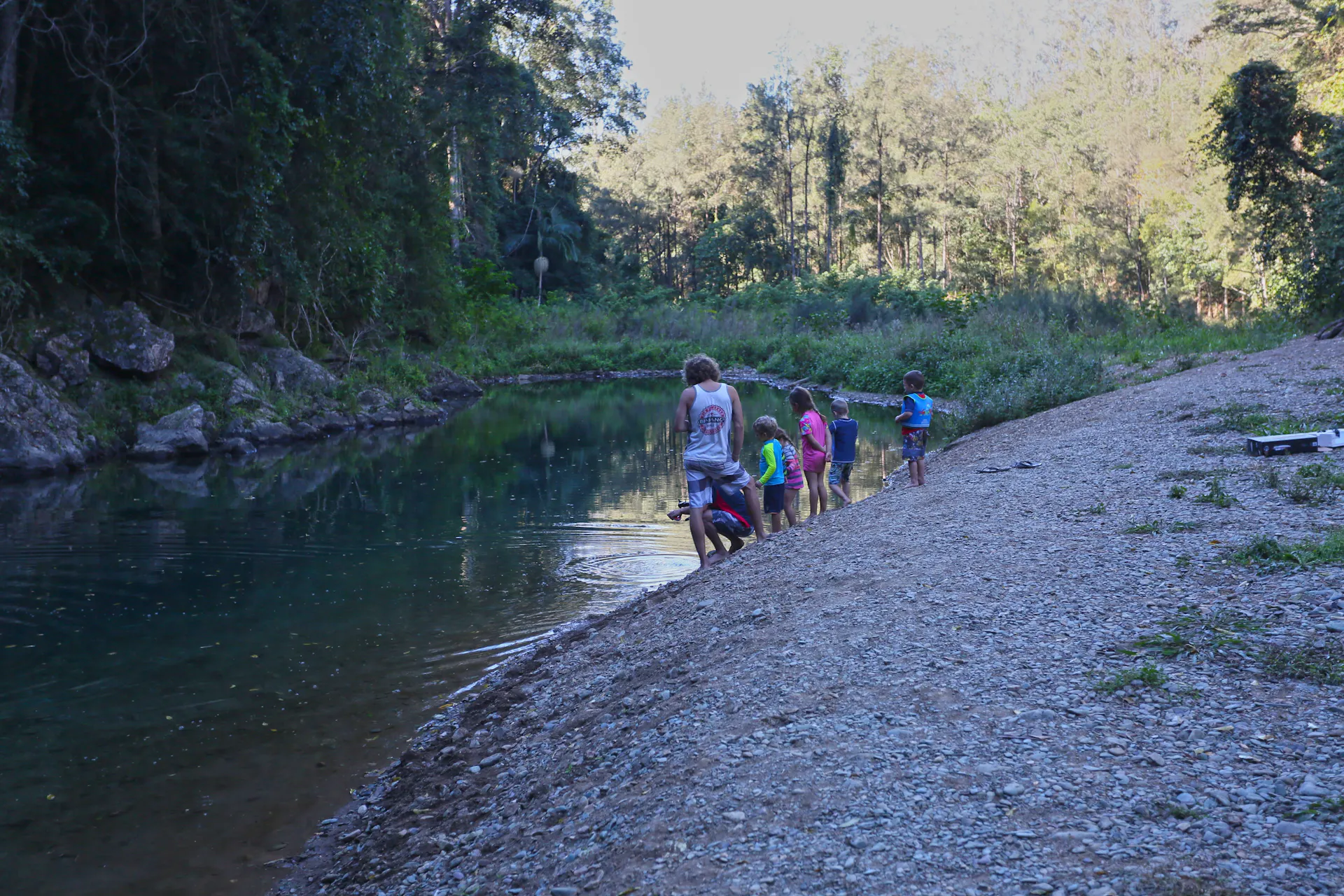A family splays near the creek edge surrounded by forest.