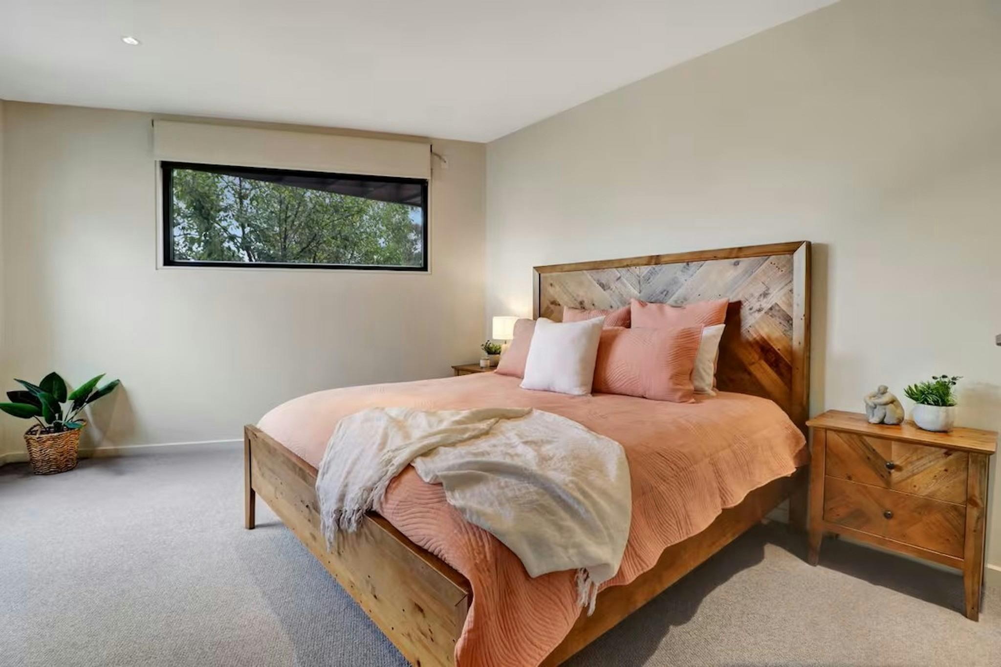 Main bedroom with timber bed and soft neutral styling at Banksia House High Country Retreat Mansfiel