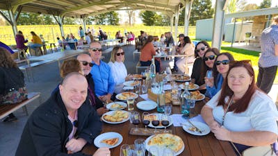 A group of people sitting at a table enjoying a meal together, with a variety of food and glasses of