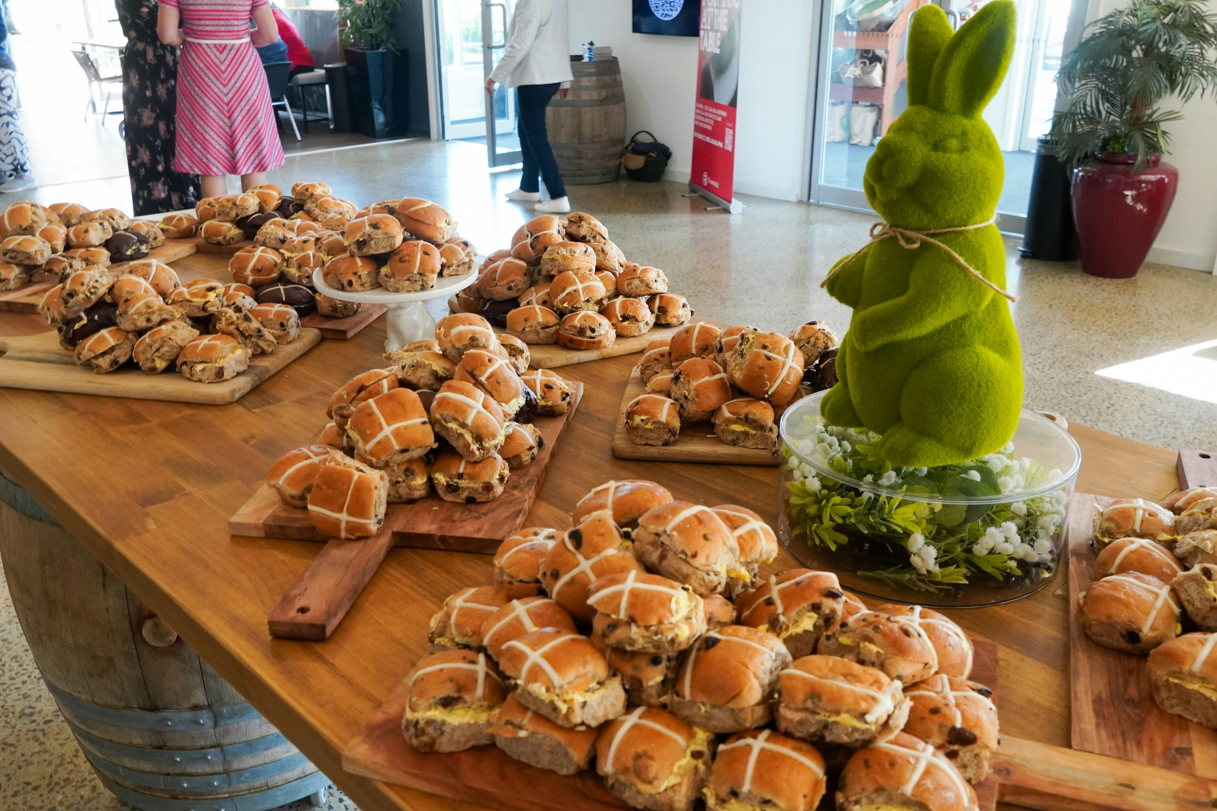 A table piled high with hot cross buns