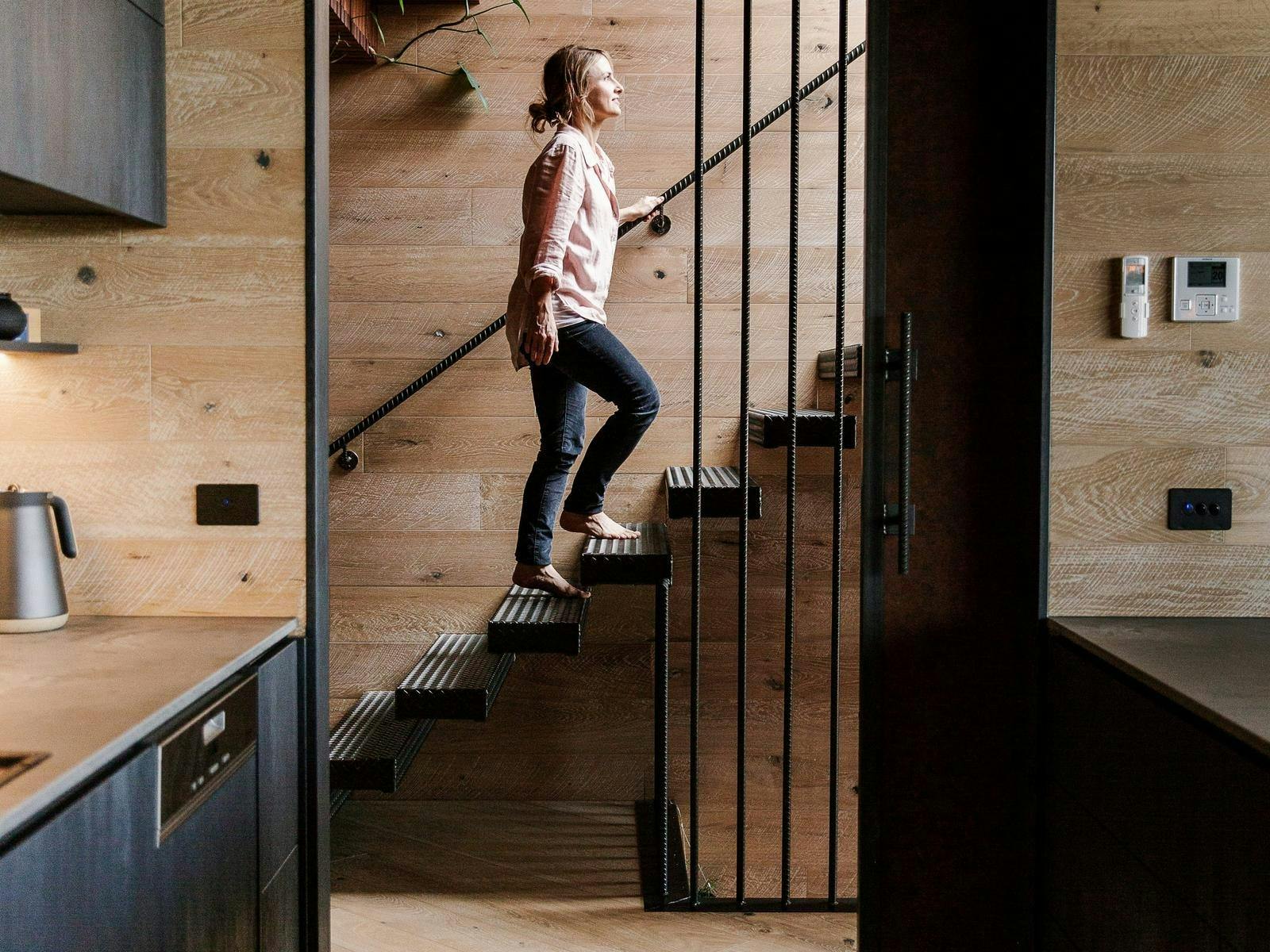 A lady walks up the designer staircase at BullerRoo Luxury Farmstay