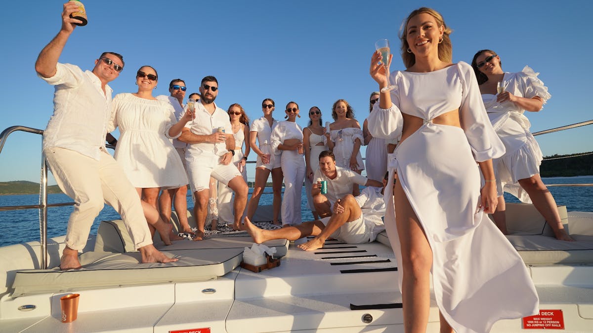 Guests dress in white on top sundeck of SV Wings III in the Whitsundays Queensland