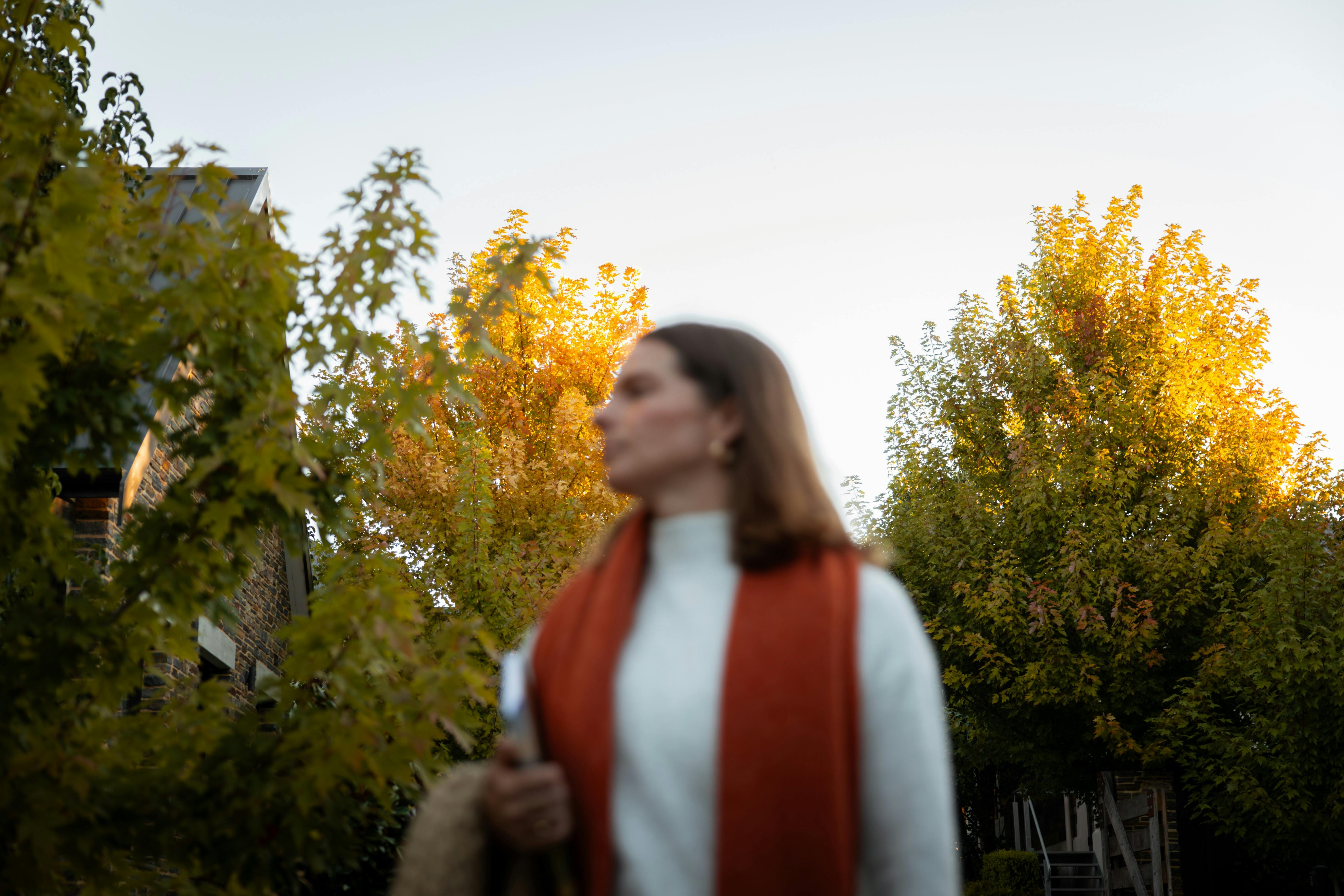 Woman walking down a driveway at Vale 194 in McLaren Vale with glowing autumn trees in the backgroun