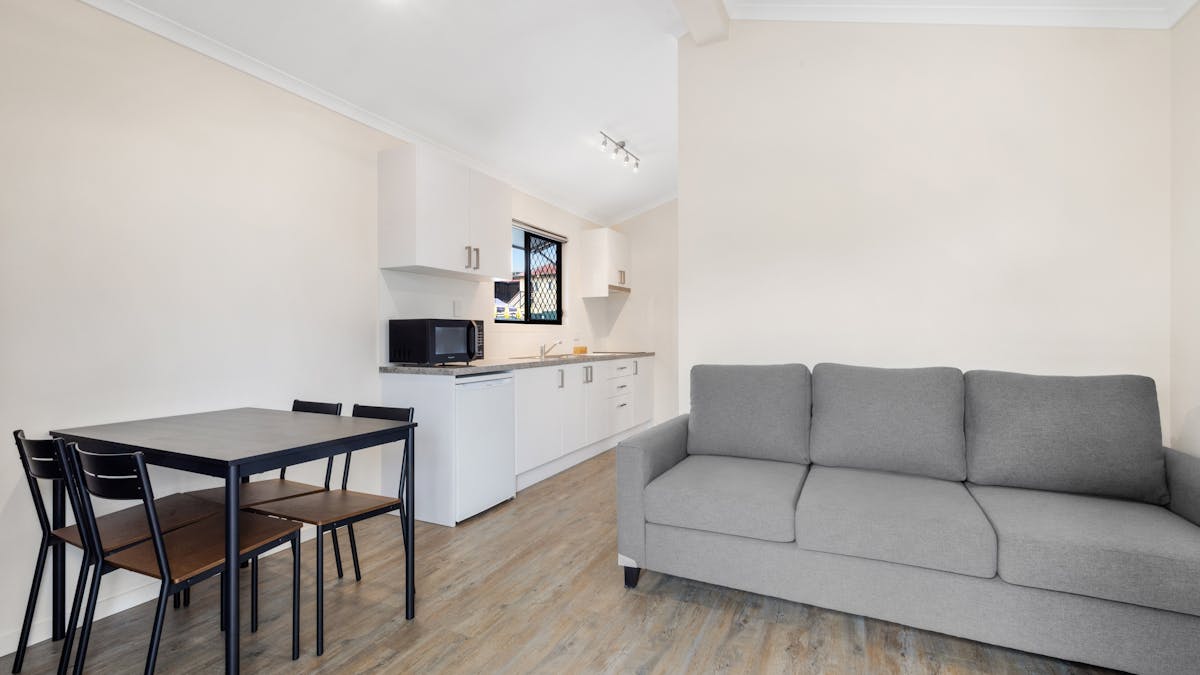 Two Bedroom lounge room with dining table, tv and kitchenette.