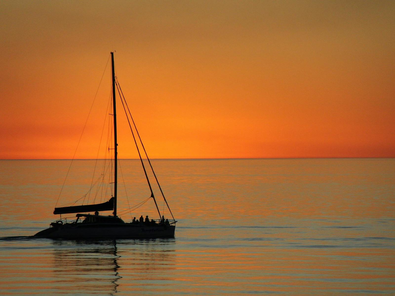 Cruising along the coastline in a catamaran with sunset