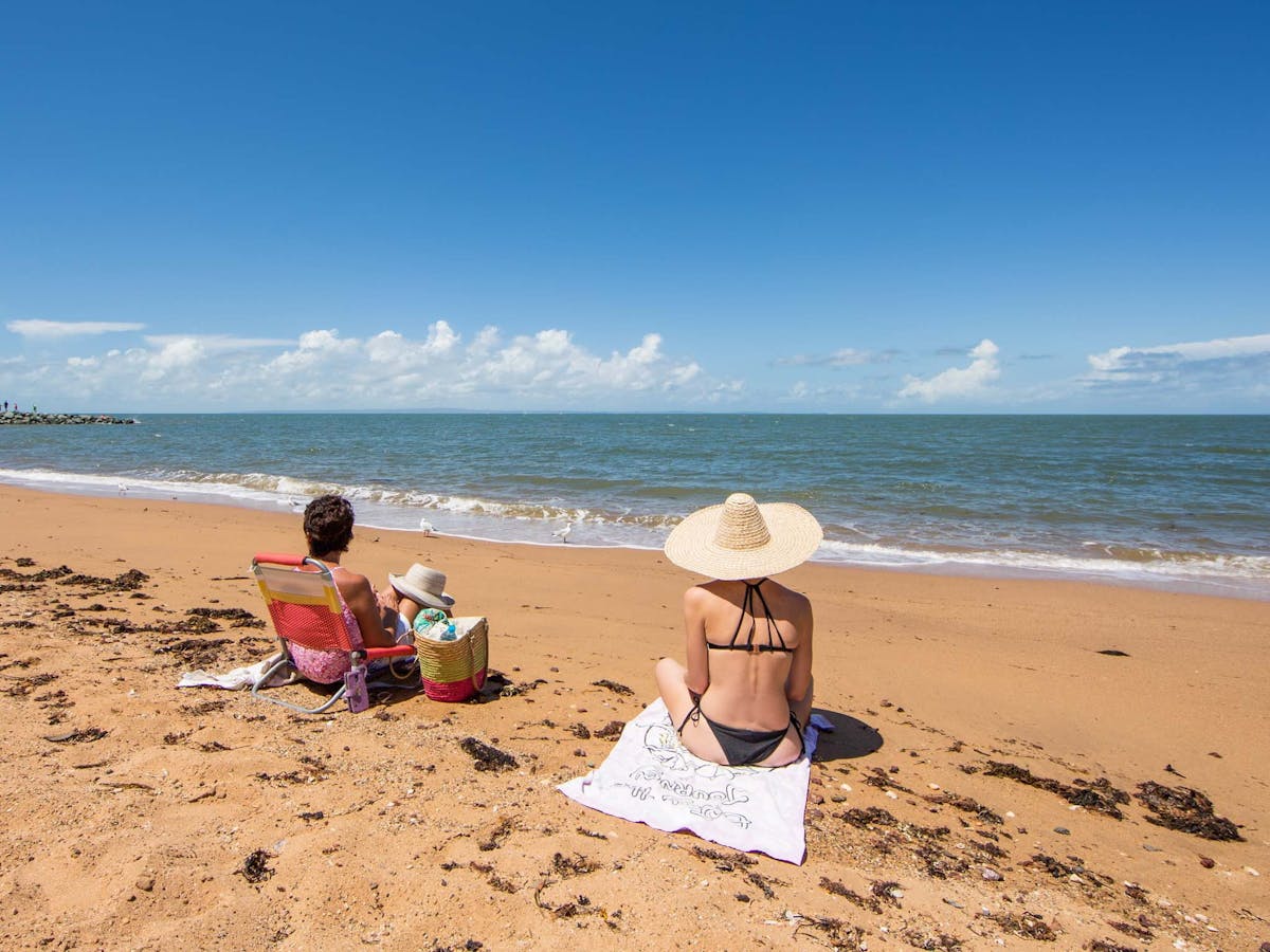 Two women sitting on the beach near Scarborough Beach Park, Moreton Bay Region