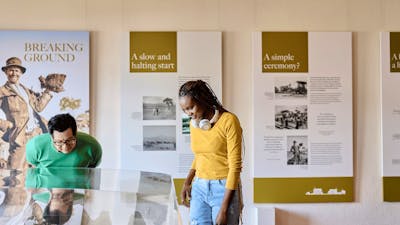 Two people observe a miniature version of Old Parliament House beneath a glass display case