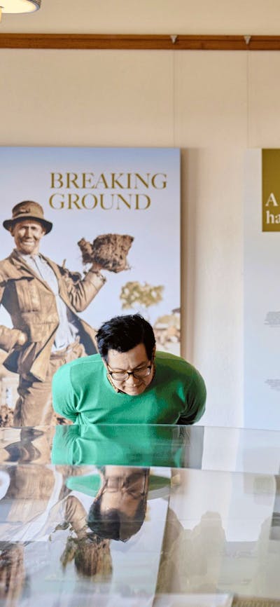 Two people observe a miniature version of Old Parliament House beneath a glass display case