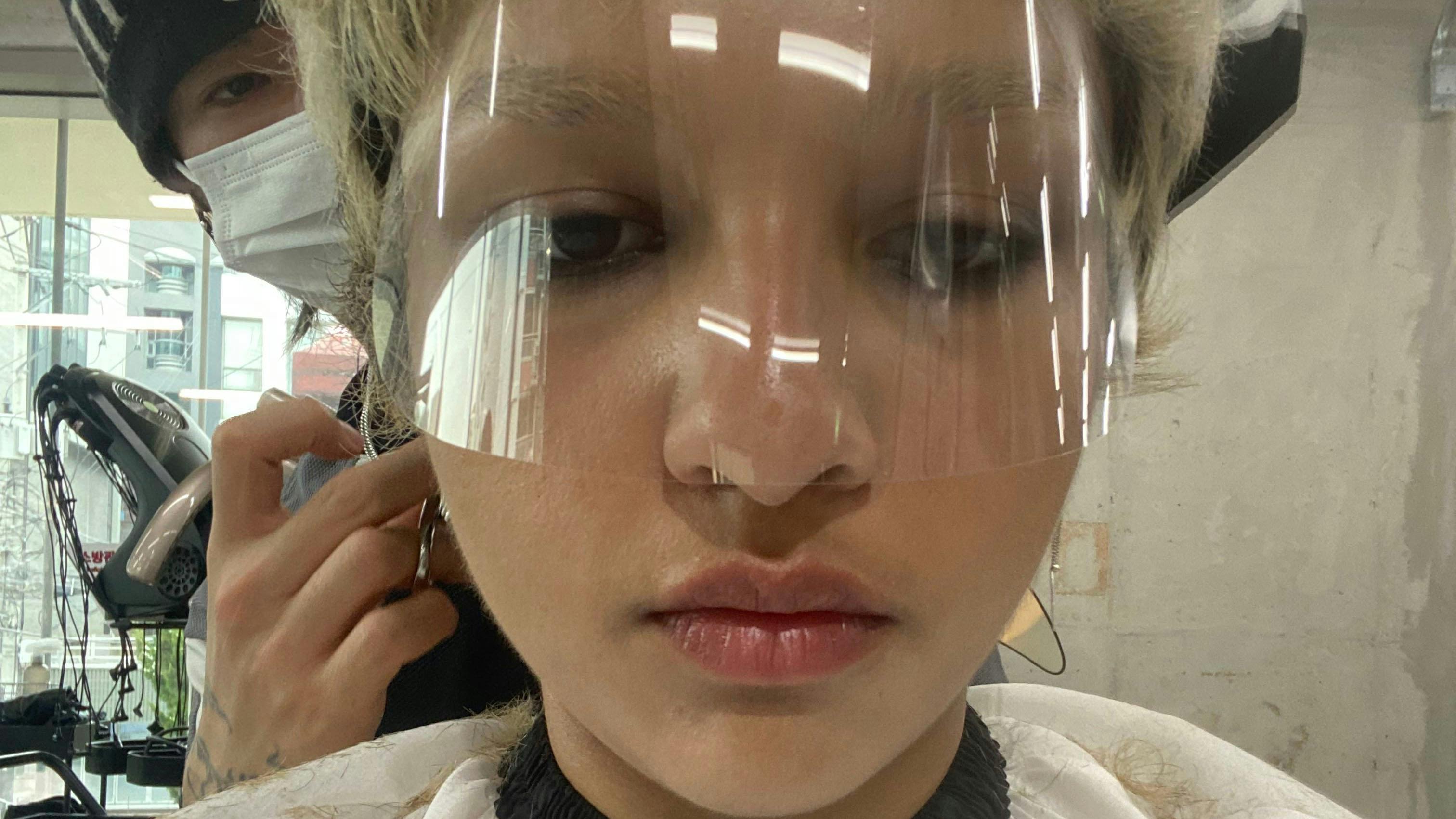 A person with a clear eye guard getting their hair cut