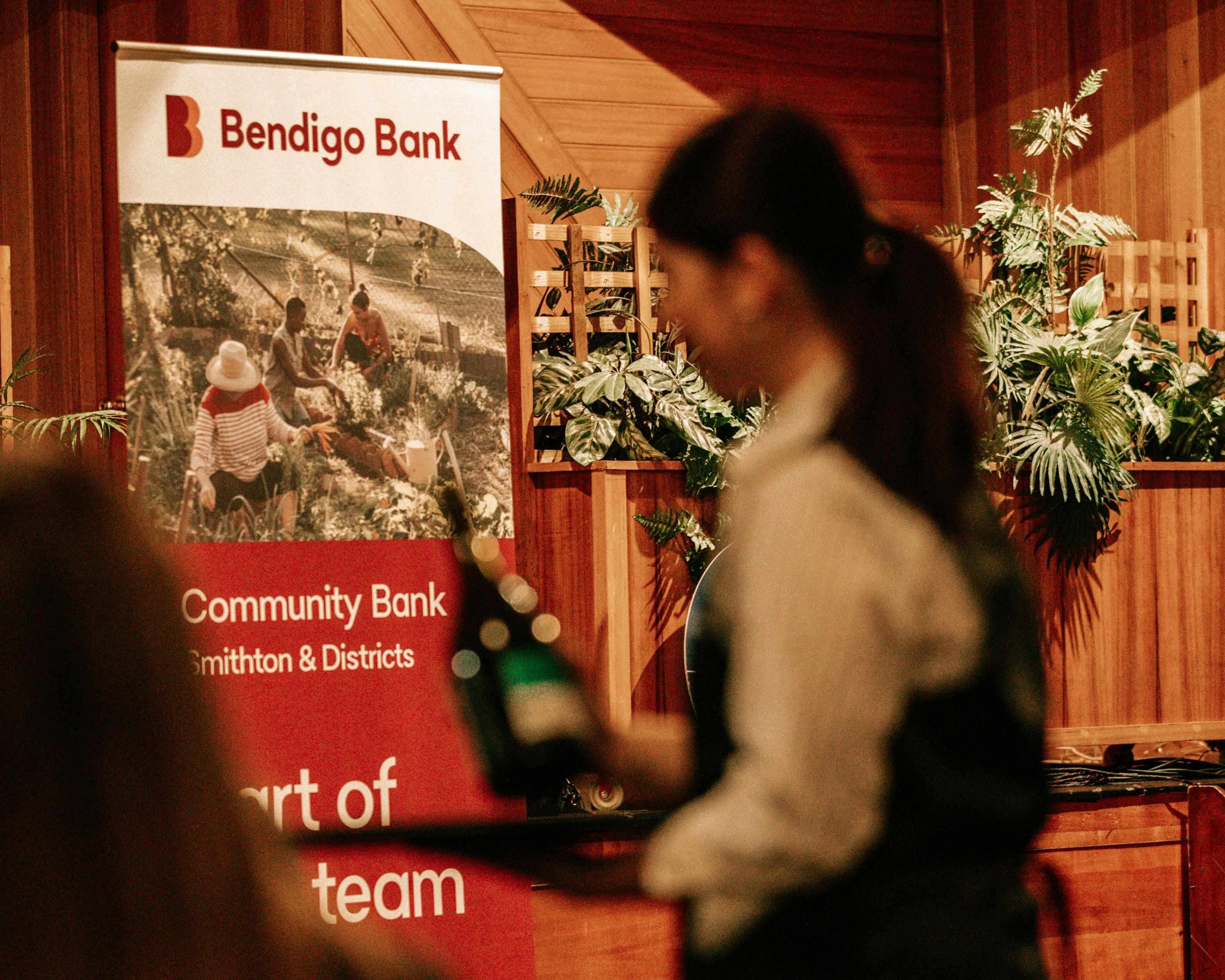 Blurred waitress with tray, Bendigo Bank red pull up banner focus