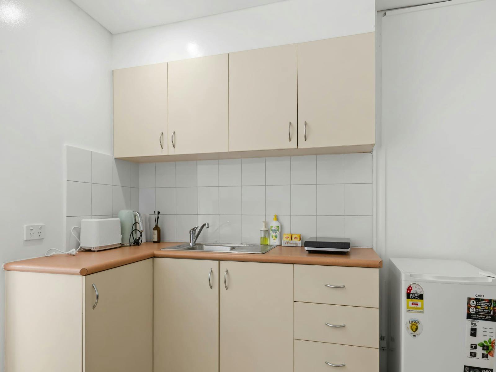 Compact and practical kitchenette with storage cabinets and essential appliances.
