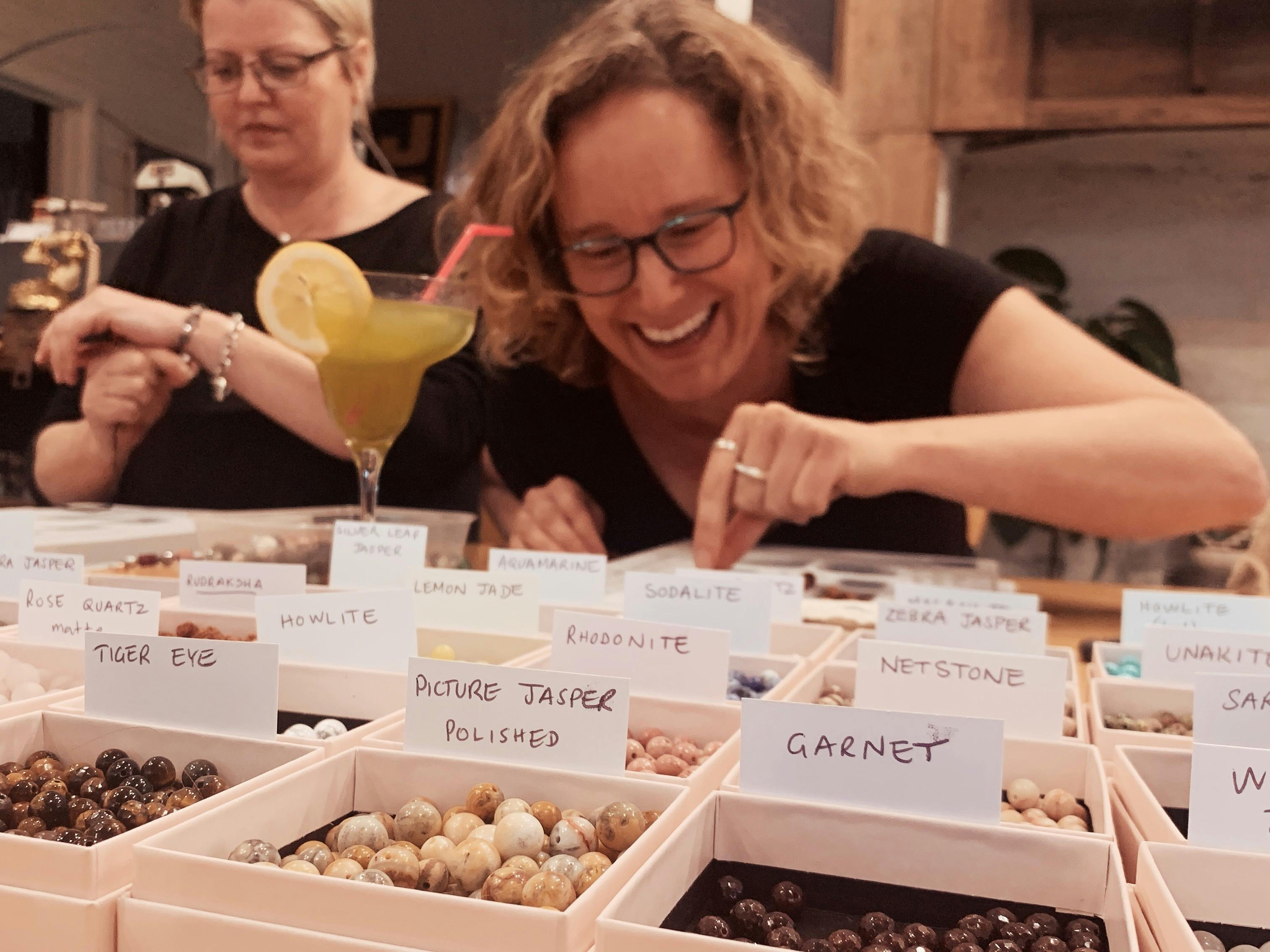 Student choosing gemstone beads from a large selection in Mala workshop