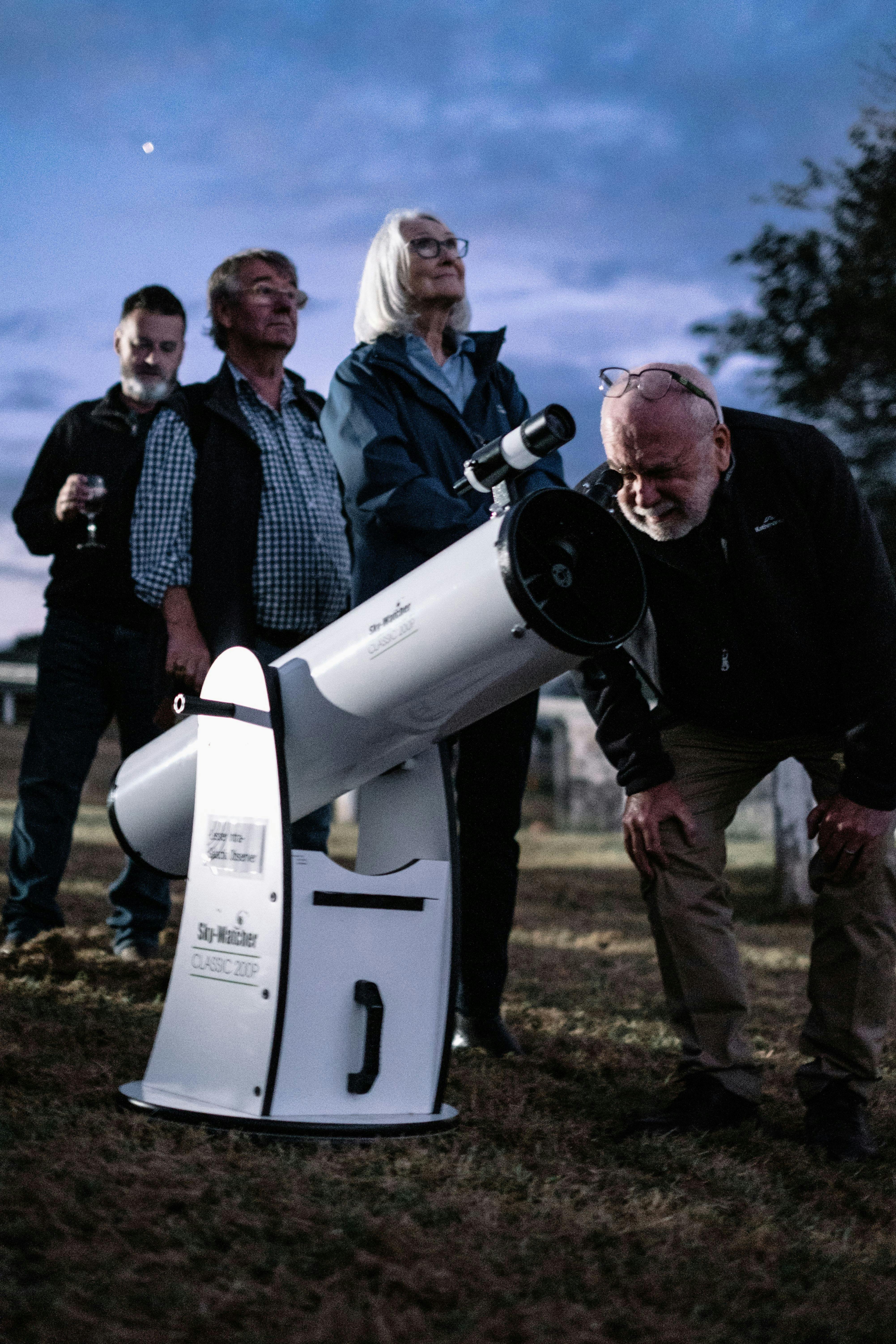 Man puts his eye to telescope to study the sky