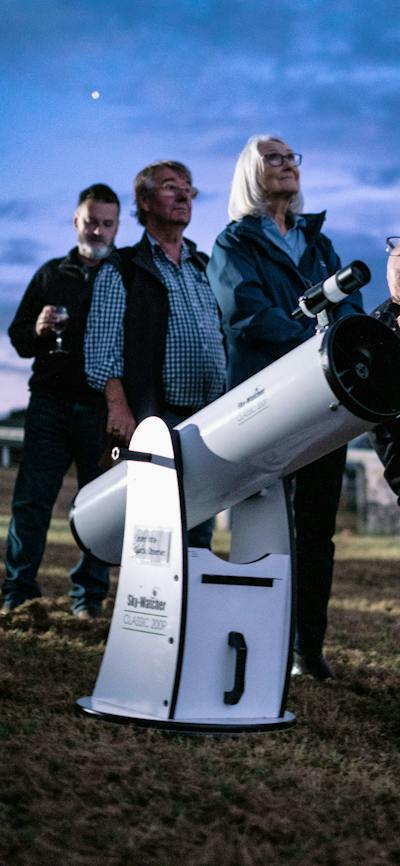 Man puts his eye to telescope to study the sky