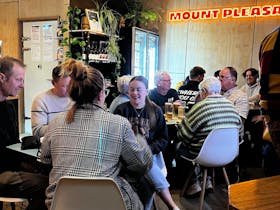 Group of people drinking inside the taproom with neon sign in background