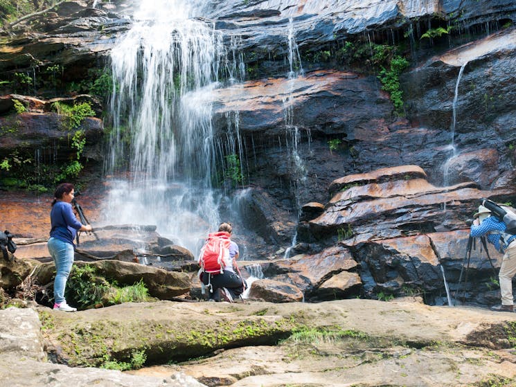 People at the base of a waterfall taking photos