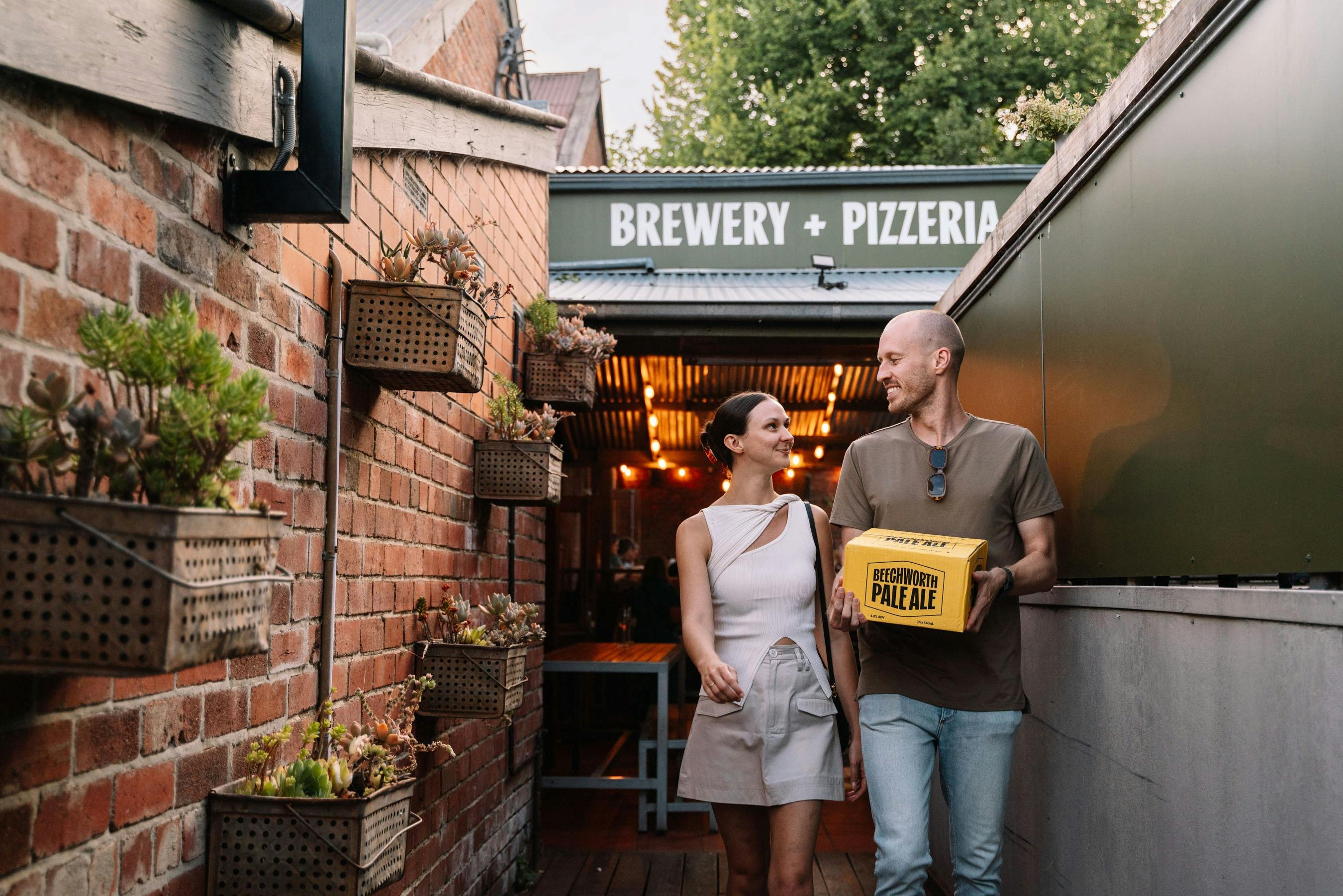 A couple walking out of the brewery with a case of Beechworth Pale Ale