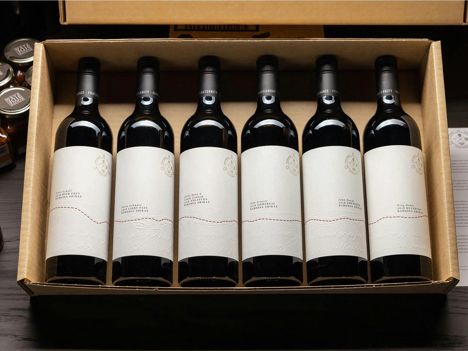 Six bottles of red wine from the Barossa Valley in a cardboard box.