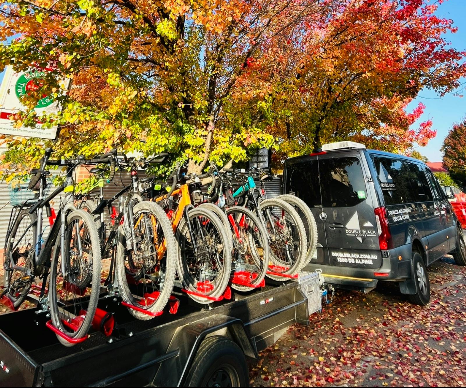 Double Black Alpine shuttle with bike trailer surrounded by trees displaying Autumn colours