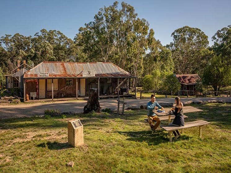 A couple enjoying morning tea at the picnic table outside The Bank Room in Yerranderie Regional Park