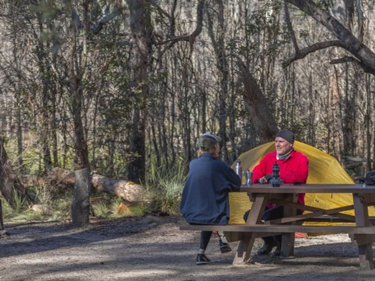 A couple sitting at a picnic table with their tent in the background at Barokee campground in