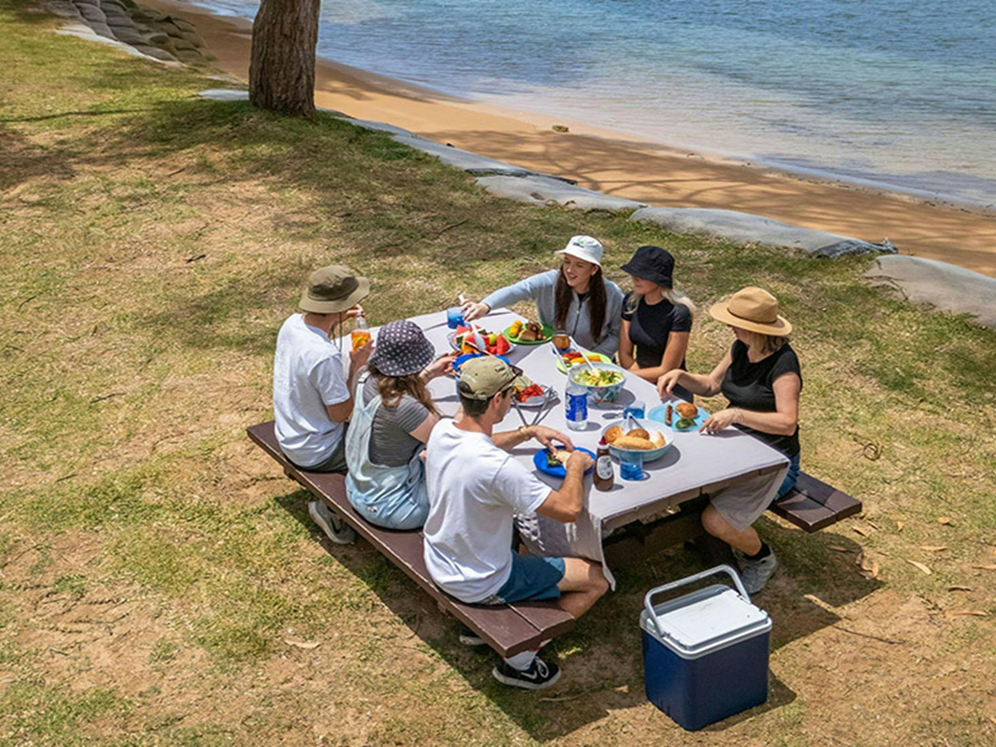A group of people eating at a picnic table by the water at The Basin campground. Credit: John