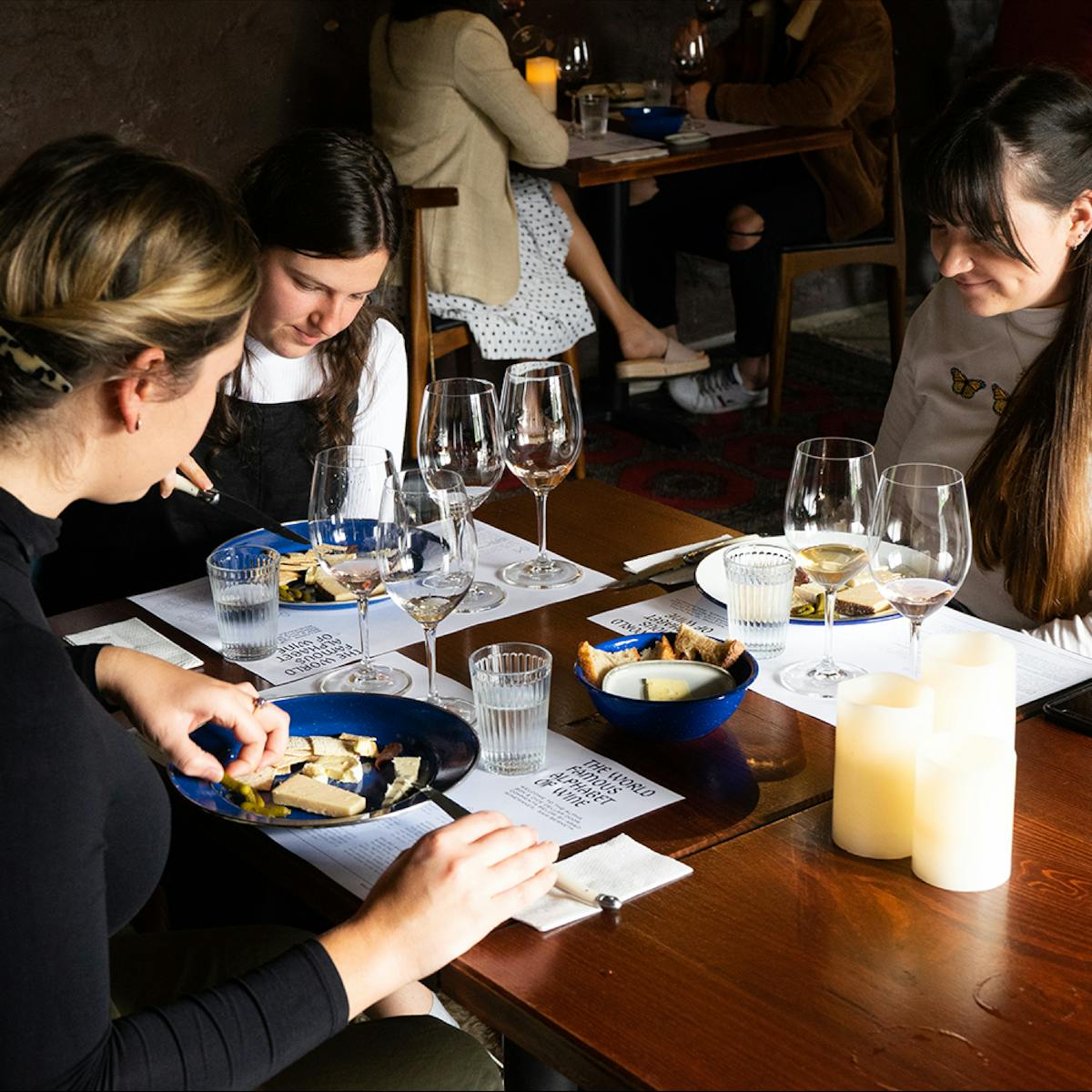 Group of girls sitting at table with wine tasting and cheese plates