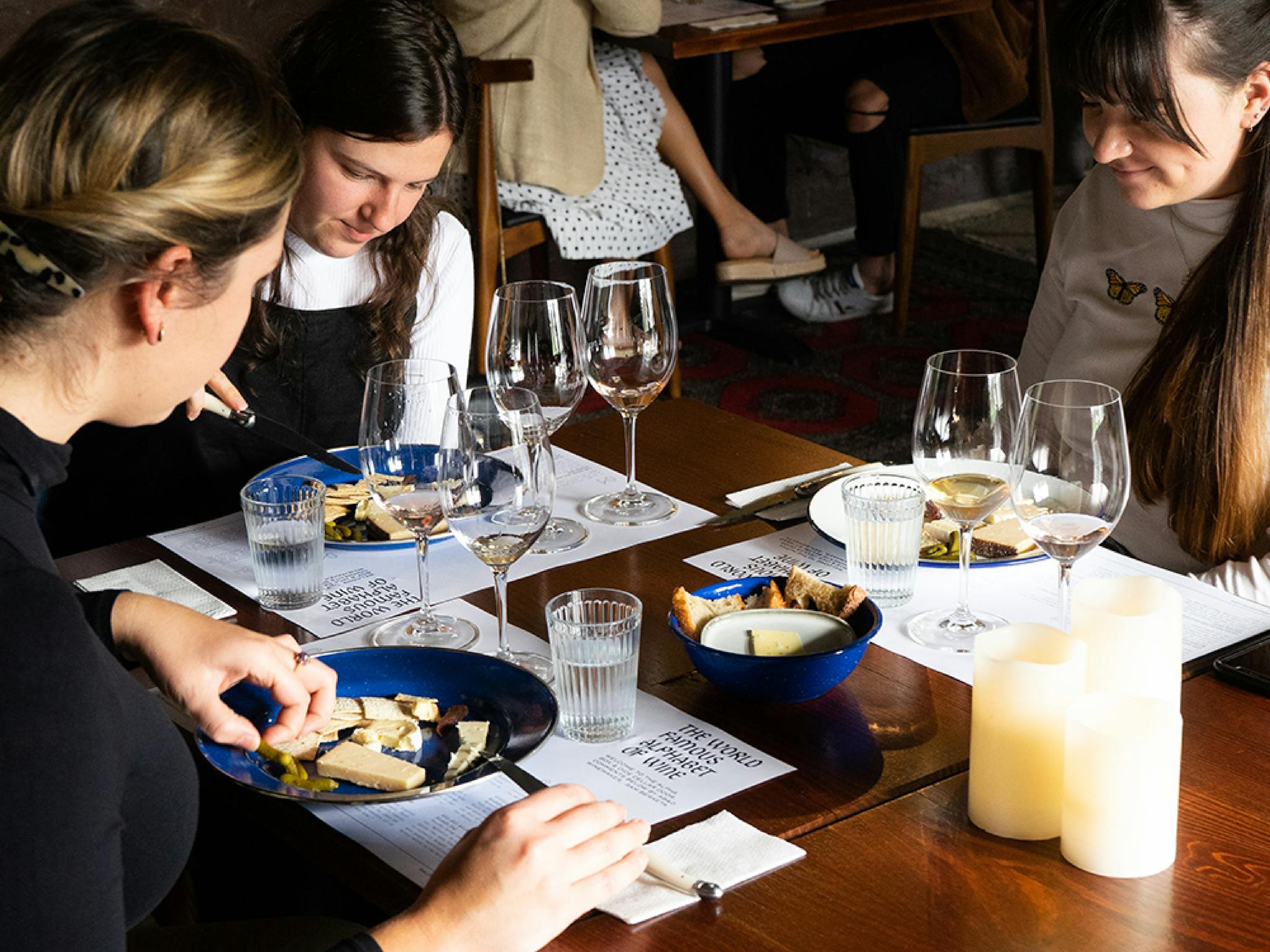 Group of girls sitting at table with wine tasting and cheese plates