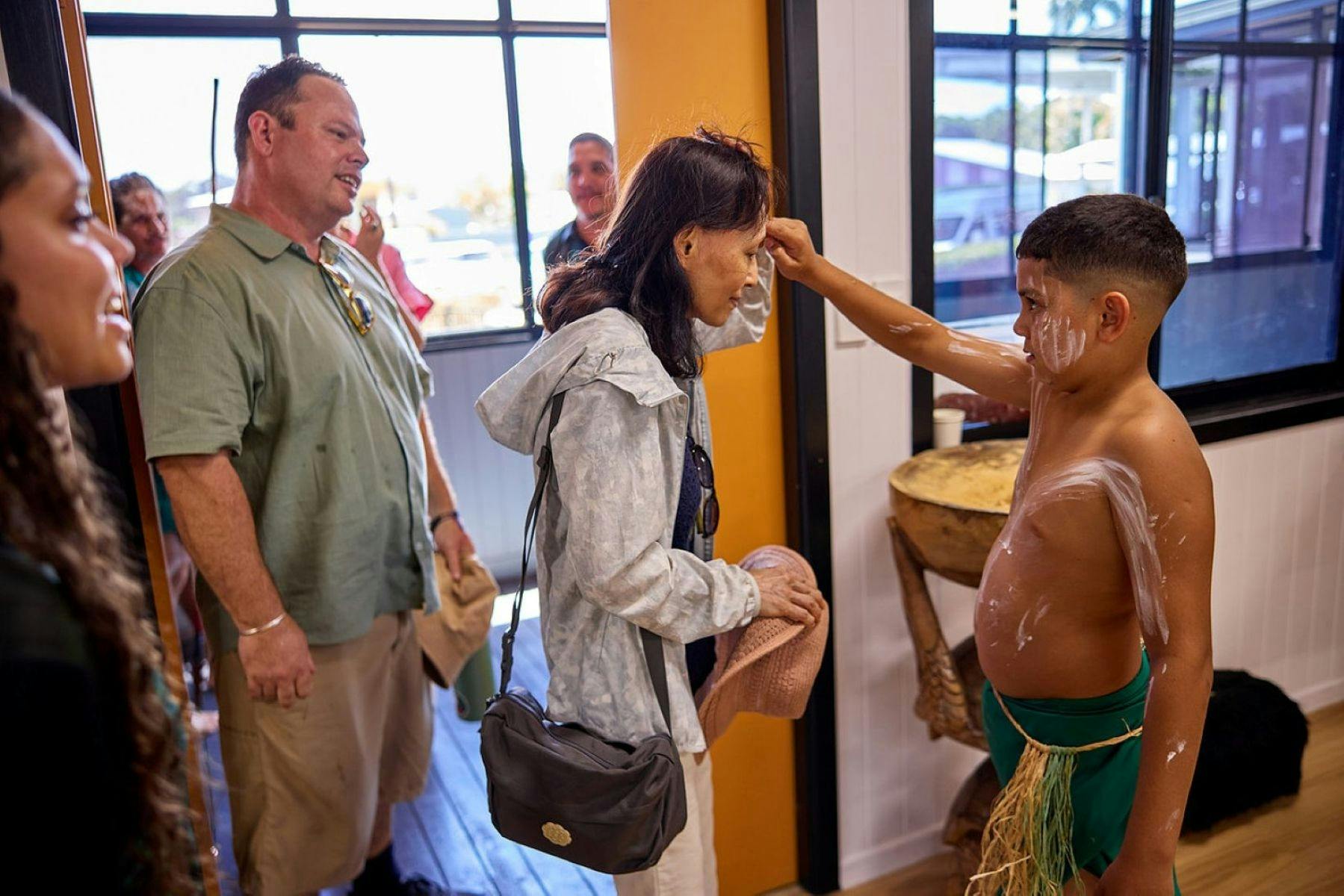 Boy paints small mark on guests as a welcoming for lunch on the Cassowary Coast Goondoi Culture Tour