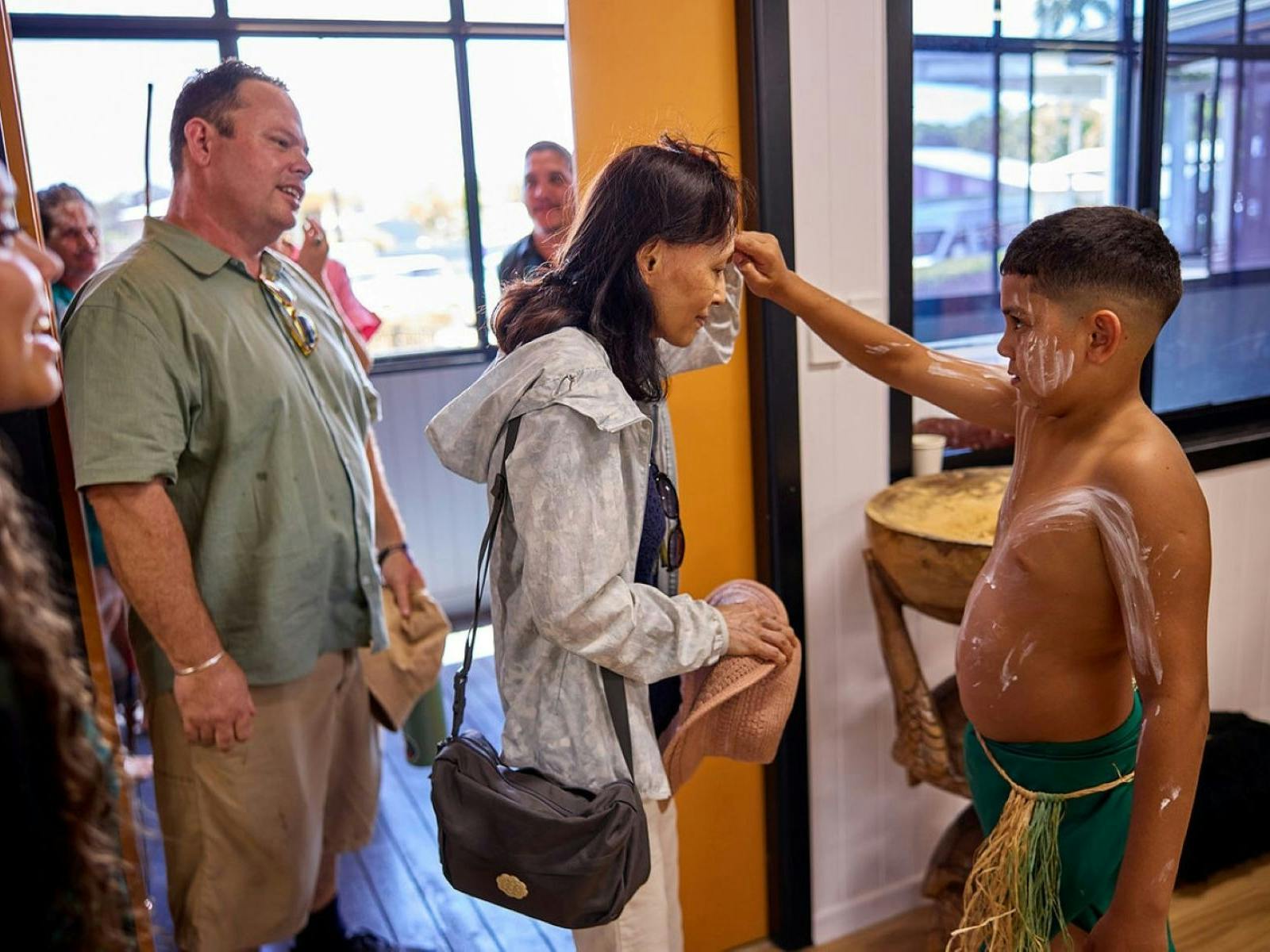 Boy paints small mark on guests as a welcoming for lunch on the Cassowary Coast Goondoi Culture Tour