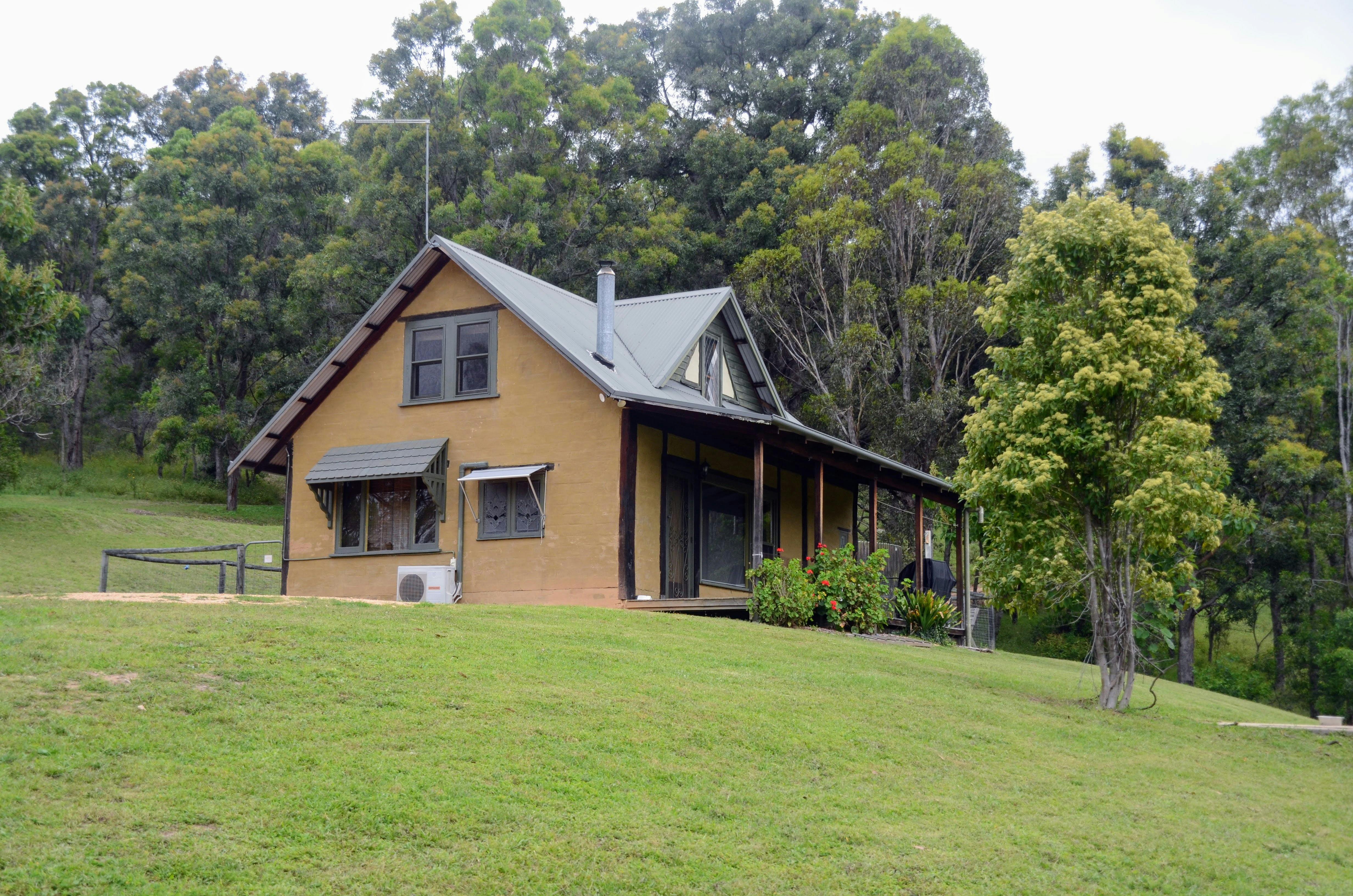 A two-storey mud brick cottage in a bush setting