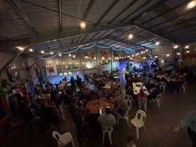 Live music gig at the brewery, people sitting at tables , musicians on the stage