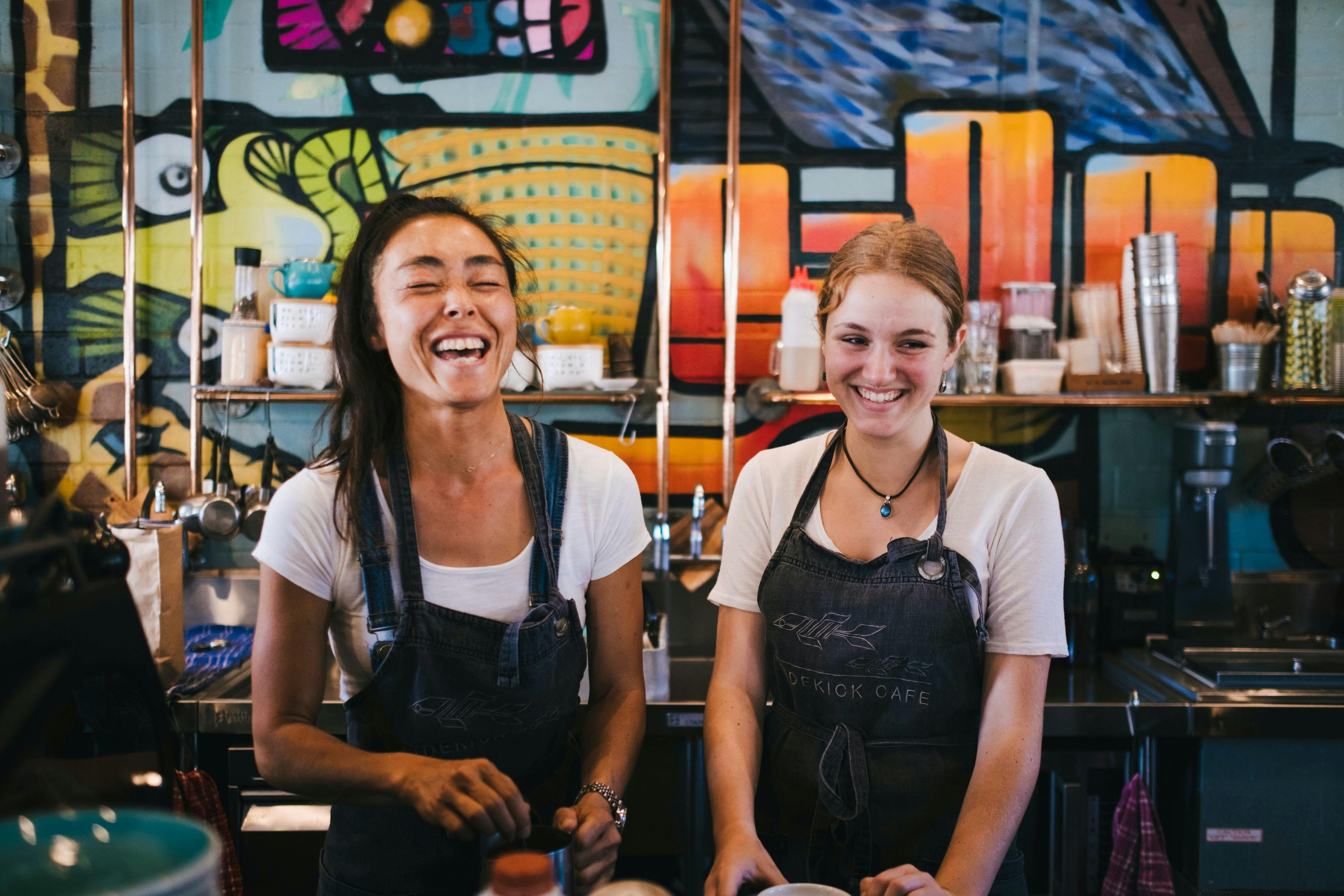 Two cafe staff smiling as they greet guests