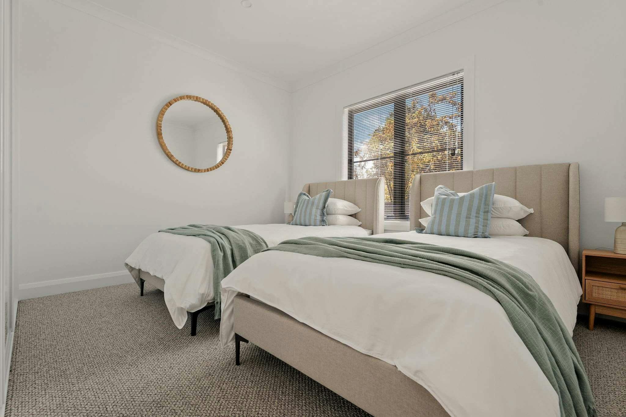2 king single beds with white linen, green throw and blue pillow case