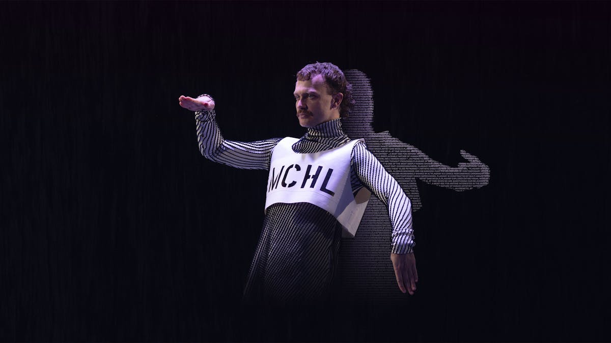 A male dancer poses in a robotic position. His shadow is filled with coloured text.