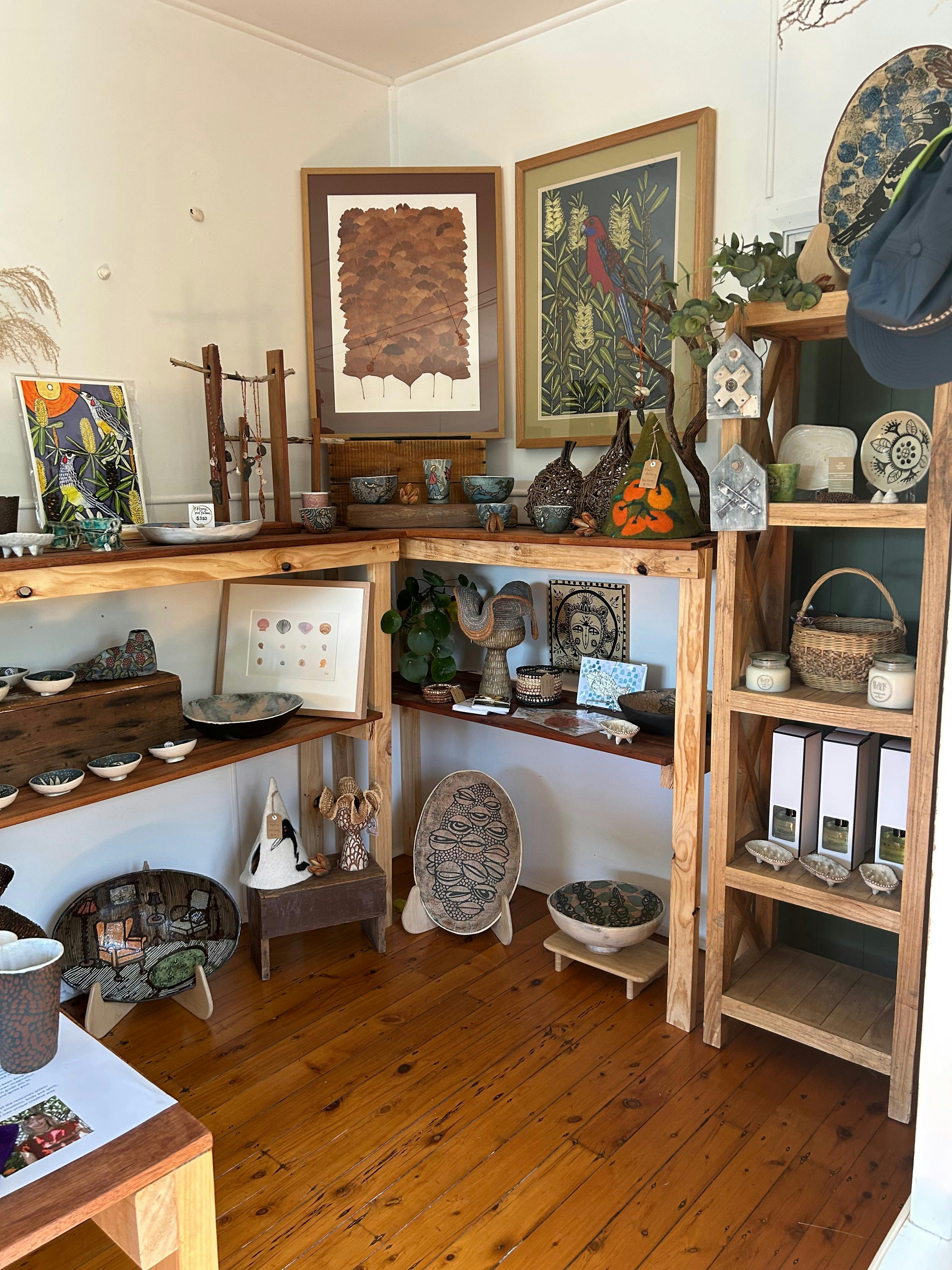 Internal shot multiple shelving showcasing original  art , ceramics, candles,  and basketwork.