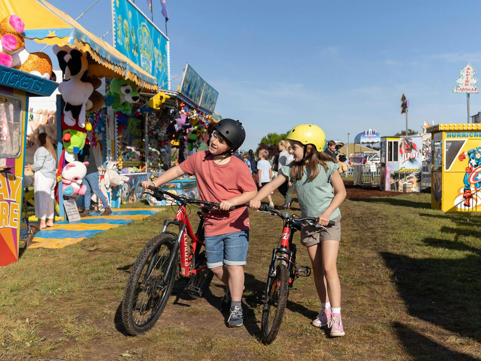 Children walking their bikes through sideshow alley at the Longford Show