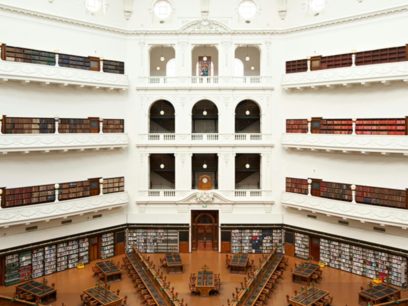 A large, bright white room that is covered in bookshelves and desks.